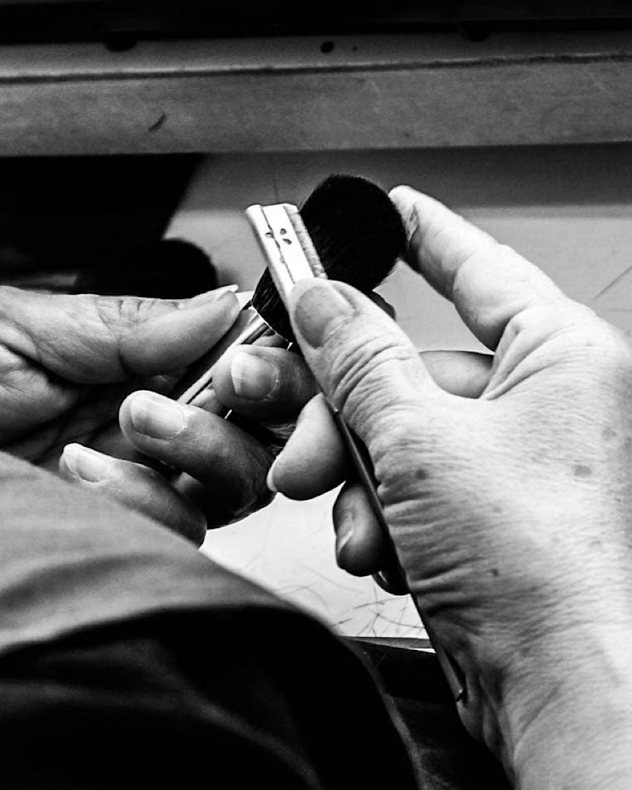 職人の手元、黒いブラシを持ち丁寧に作業する様子のモノクロ写真